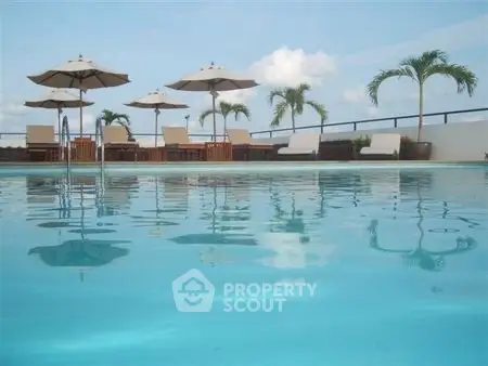 Luxurious rooftop pool with sun loungers and palm trees, perfect for relaxation.