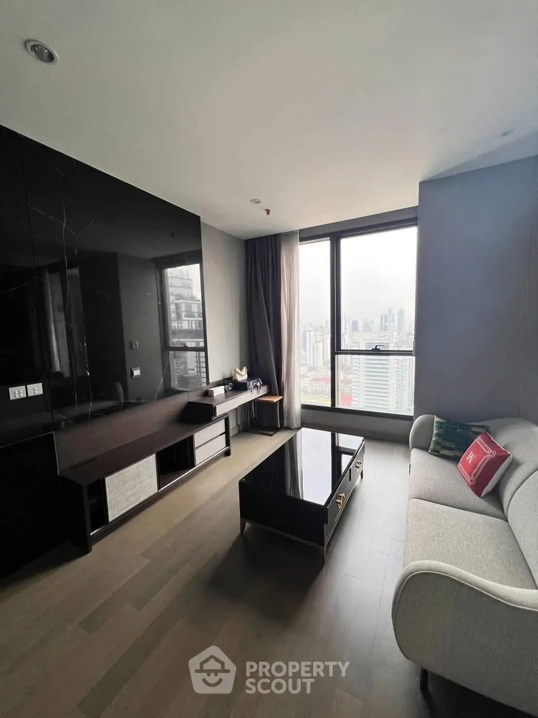 Modern living room with city view, sleek furniture, and large windows in a high-rise apartment.