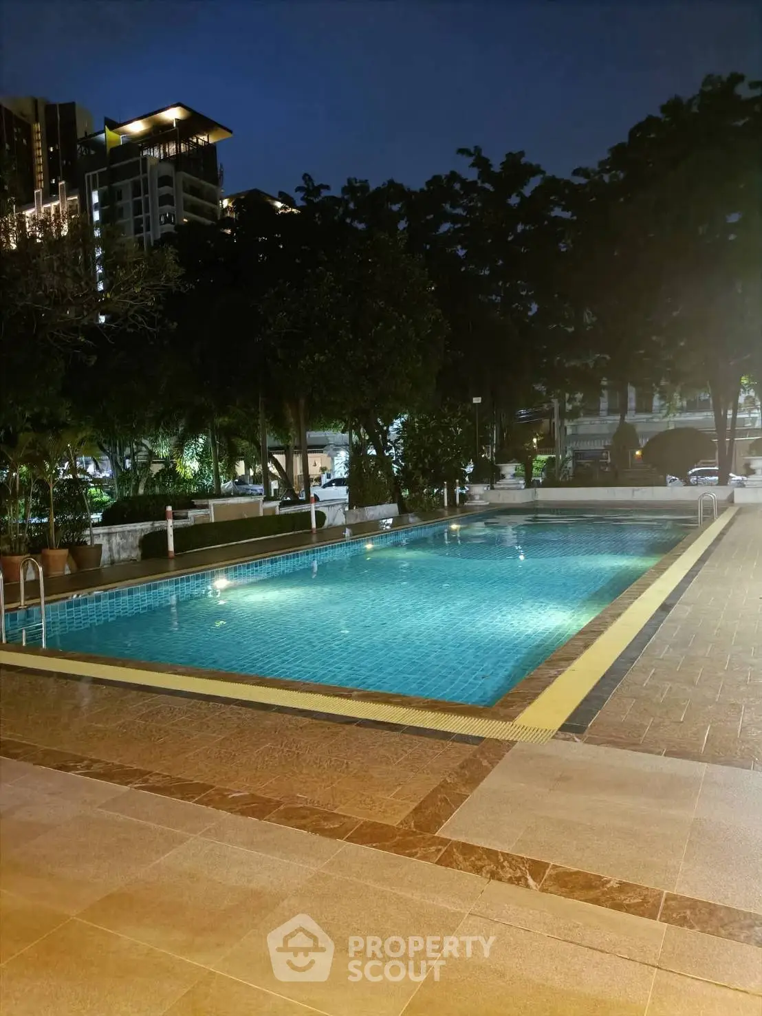 Luxurious outdoor pool area with ambient lighting in a modern residential complex.