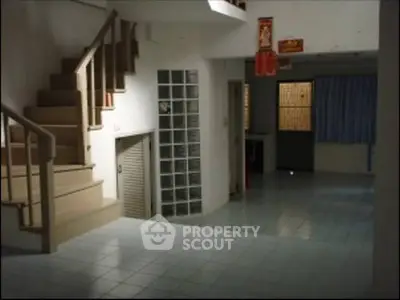 Spacious interior with tiled flooring and staircase, ideal for creative renovation.