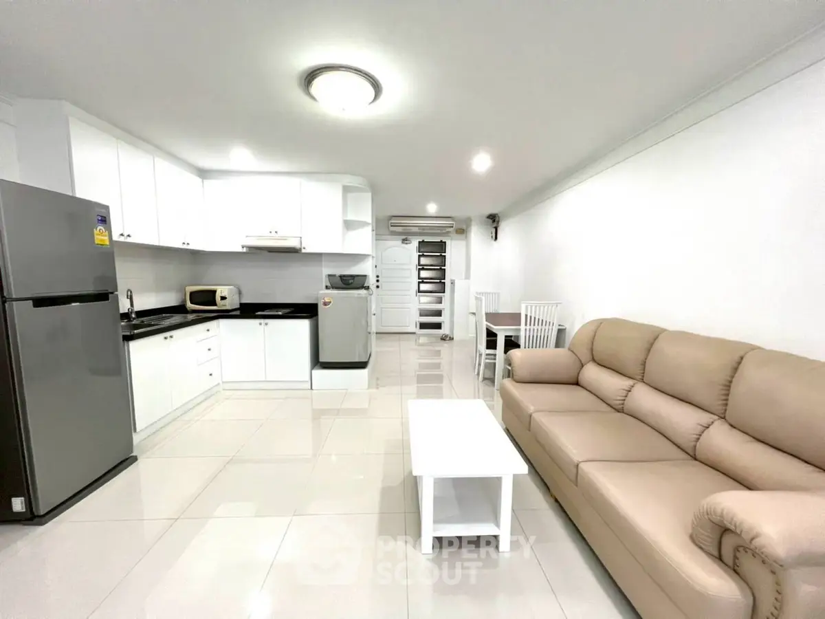 Modern open-layout kitchen and living room with sleek appliances and cozy seating.