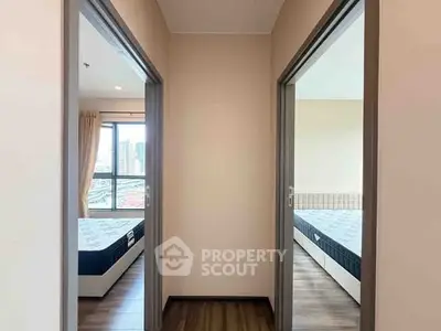 Modern apartment with two bedrooms and city view, featuring wooden flooring and large windows.