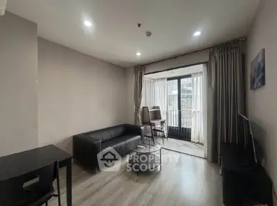 Modern living room with sleek black sofa and large windows offering city views.