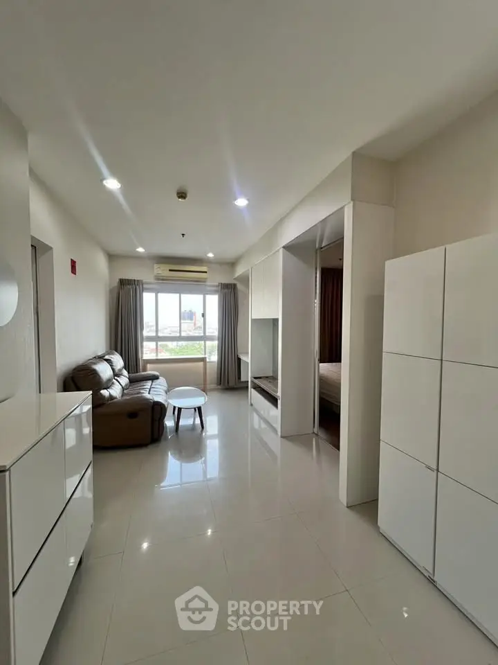 Spacious modern living room with sleek furniture and large window offering natural light.