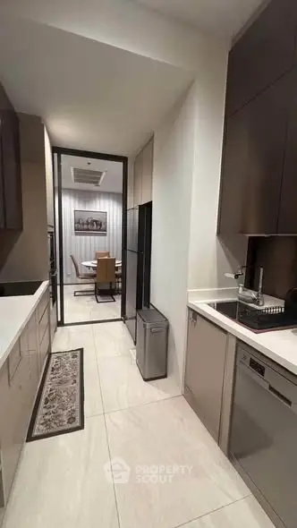 Modern kitchen with sleek cabinetry and open layout leading to dining area