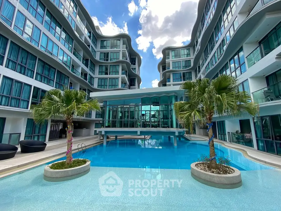 Luxurious modern building with stunning pool and palm trees, perfect for resort-style living.