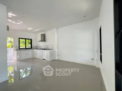 Modern kitchen with sleek white cabinets and gas stove, ample natural light and glossy tile flooring.