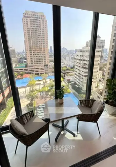 Stunning city view from a high-rise balcony with cozy seating area.