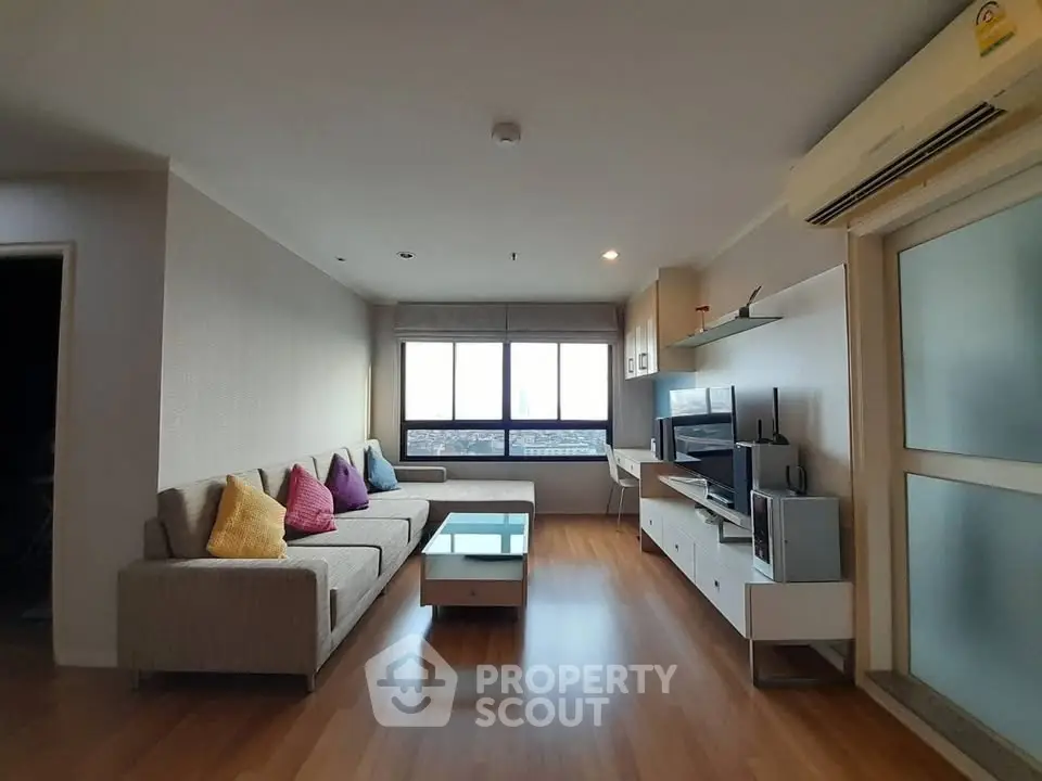Spacious modern living room with large windows and stylish decor in a high-rise apartment.