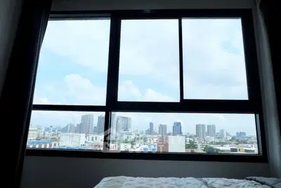 Stunning cityscape view from a modern apartment window, showcasing urban skyline and bright blue sky.