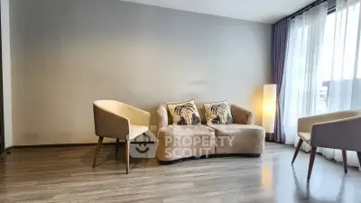 Modern living room with cozy sofa and elegant armchairs, featuring floor-to-ceiling windows for natural light.