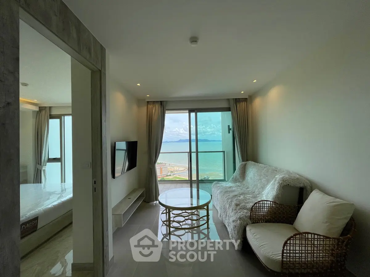 Modern living room with stunning ocean view and cozy furnishings in a high-rise apartment.