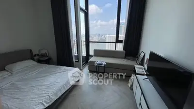 Modern bedroom with large windows offering stunning city views and sleek furniture.