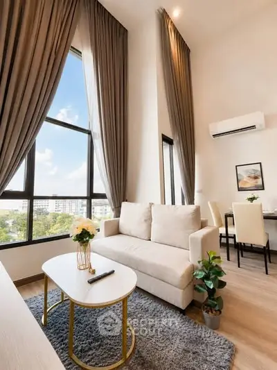 Modern living room with high ceilings, large windows, and elegant decor in a stylish apartment.