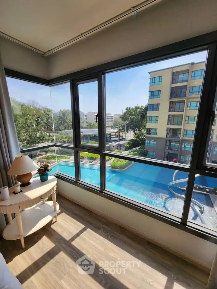 Stunning corner unit with panoramic pool view from spacious living room window.