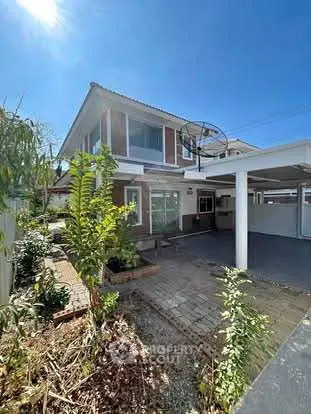 Charming two-story house with spacious driveway and lush garden under clear blue sky.