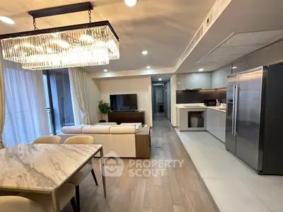 Luxurious open-plan living room and kitchen with elegant chandelier and modern appliances.