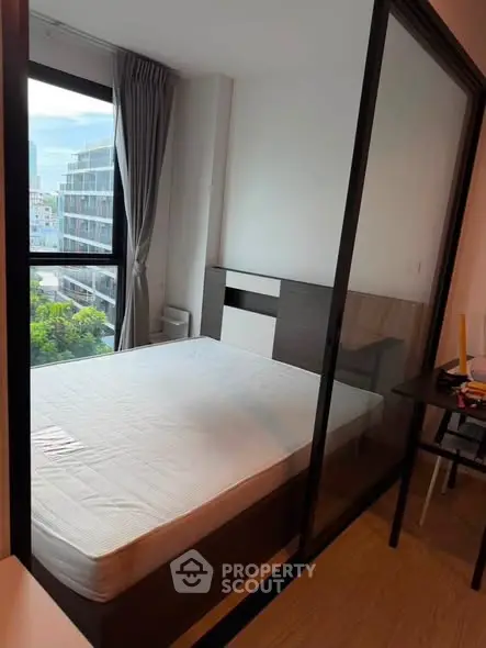 Modern bedroom with large window and city view, featuring sleek design and natural light.