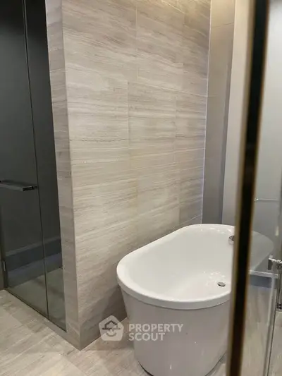 Modern bathroom with elegant freestanding bathtub and sleek glass shower enclosure.