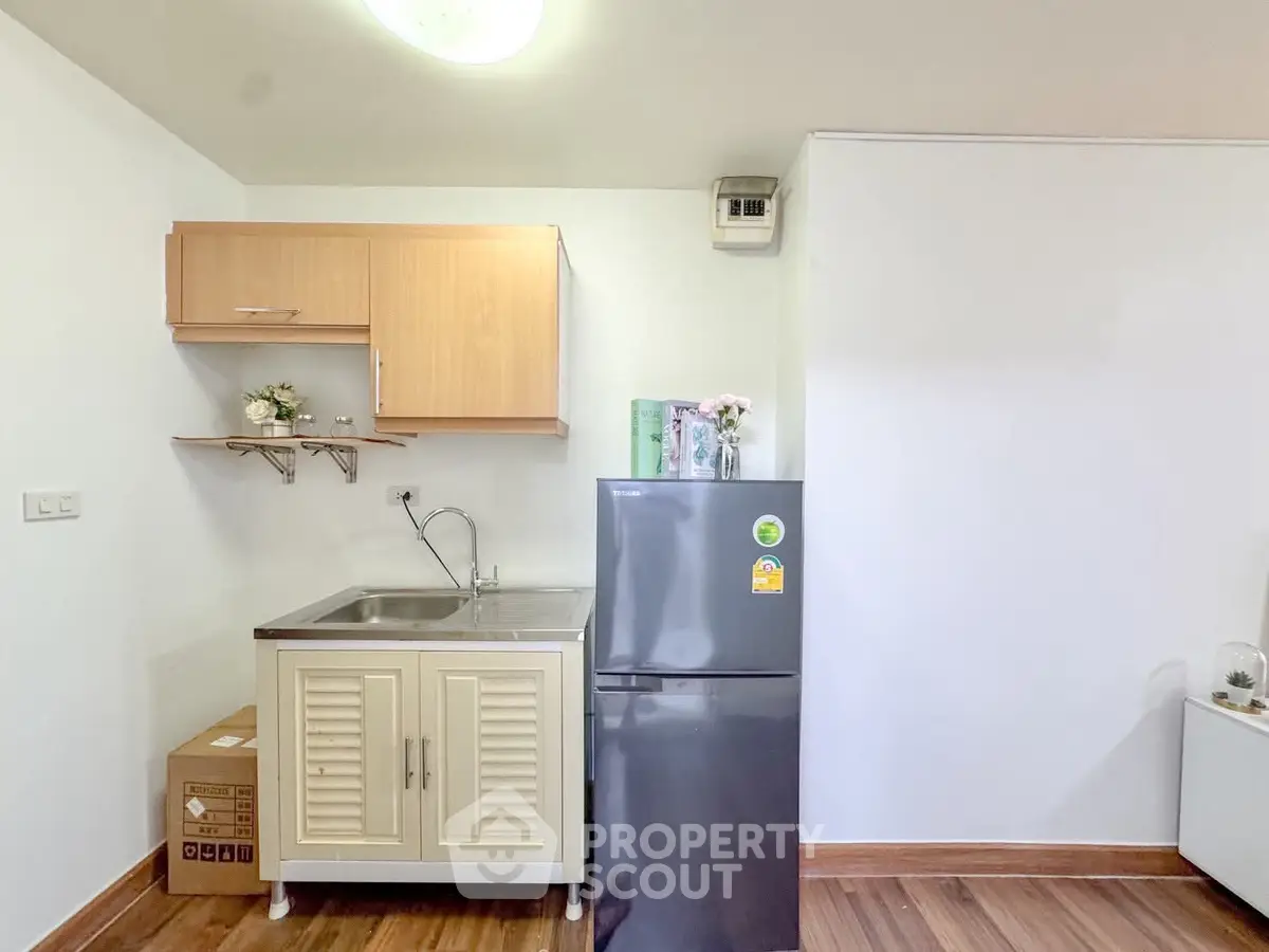 Compact kitchen with modern fridge and wooden cabinets in cozy apartment