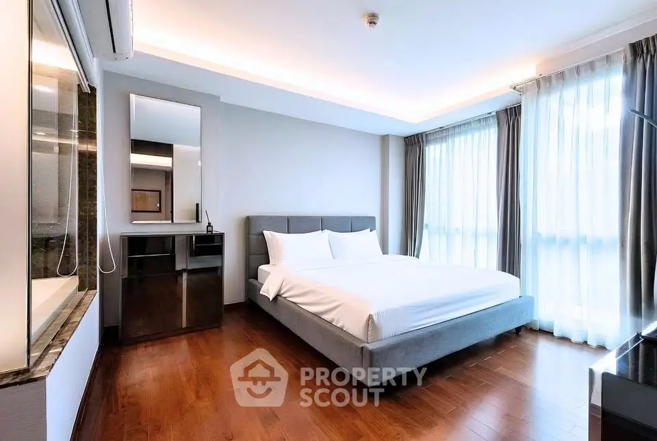 Spacious modern bedroom with elegant decor and large windows for natural light.