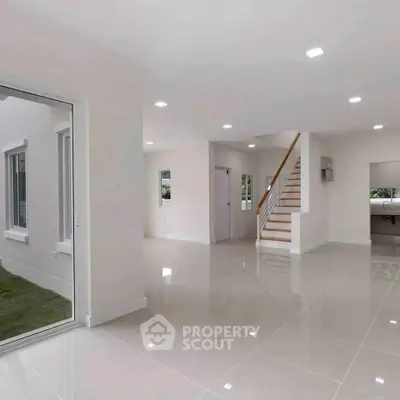 Spacious modern living room with glossy tile flooring and staircase in a bright open-plan home.