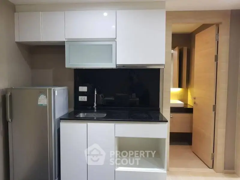 Modern compact kitchen with sleek cabinetry and built-in appliances in a stylish apartment.