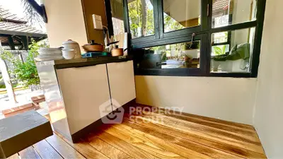 Charming outdoor kitchen with wooden flooring and lush garden view, perfect for al fresco dining.