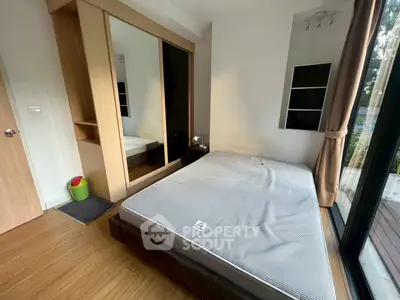 Modern bedroom with large window and wooden flooring, featuring a spacious wardrobe and minimalist design.