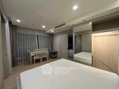 Spacious bedroom with modern furnishings and large windows offering city views.
