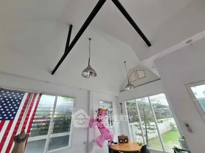 Bright living room with high ceiling and garden view, featuring unique decor and ample natural light.