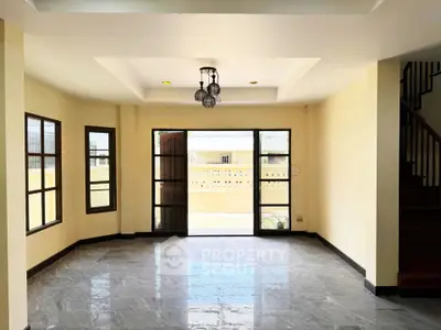 Spacious living room with large windows and modern lighting, perfect for natural light and comfort.