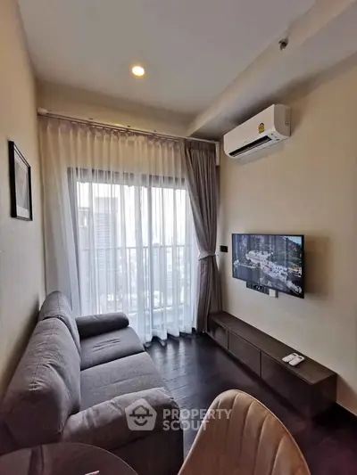 Modern living room with city view, featuring a cozy sofa, wall-mounted TV, and air conditioning.