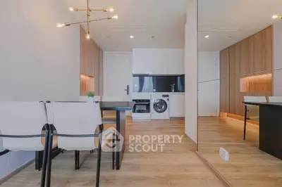 Modern dining area with sleek kitchen featuring built-in appliances and stylish lighting.