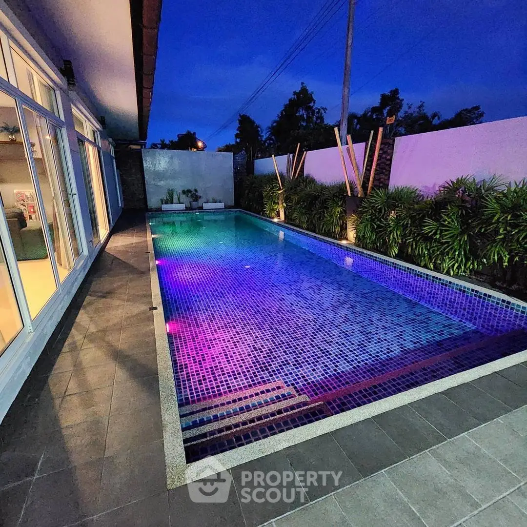 Stunning illuminated pool area with modern design and lush greenery