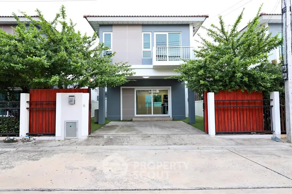 Modern two-story house with gated entrance and lush greenery