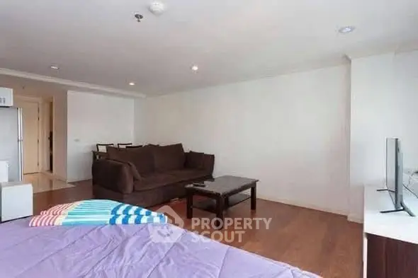 Spacious living room with modern furniture and wooden flooring in a cozy apartment.