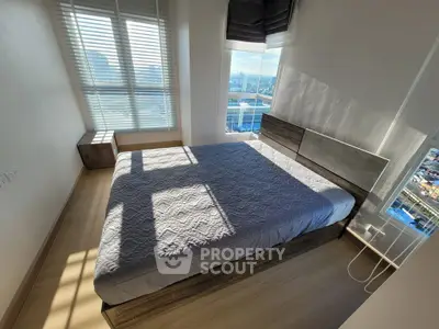 Modern bedroom with large windows offering stunning city views and ample natural light.