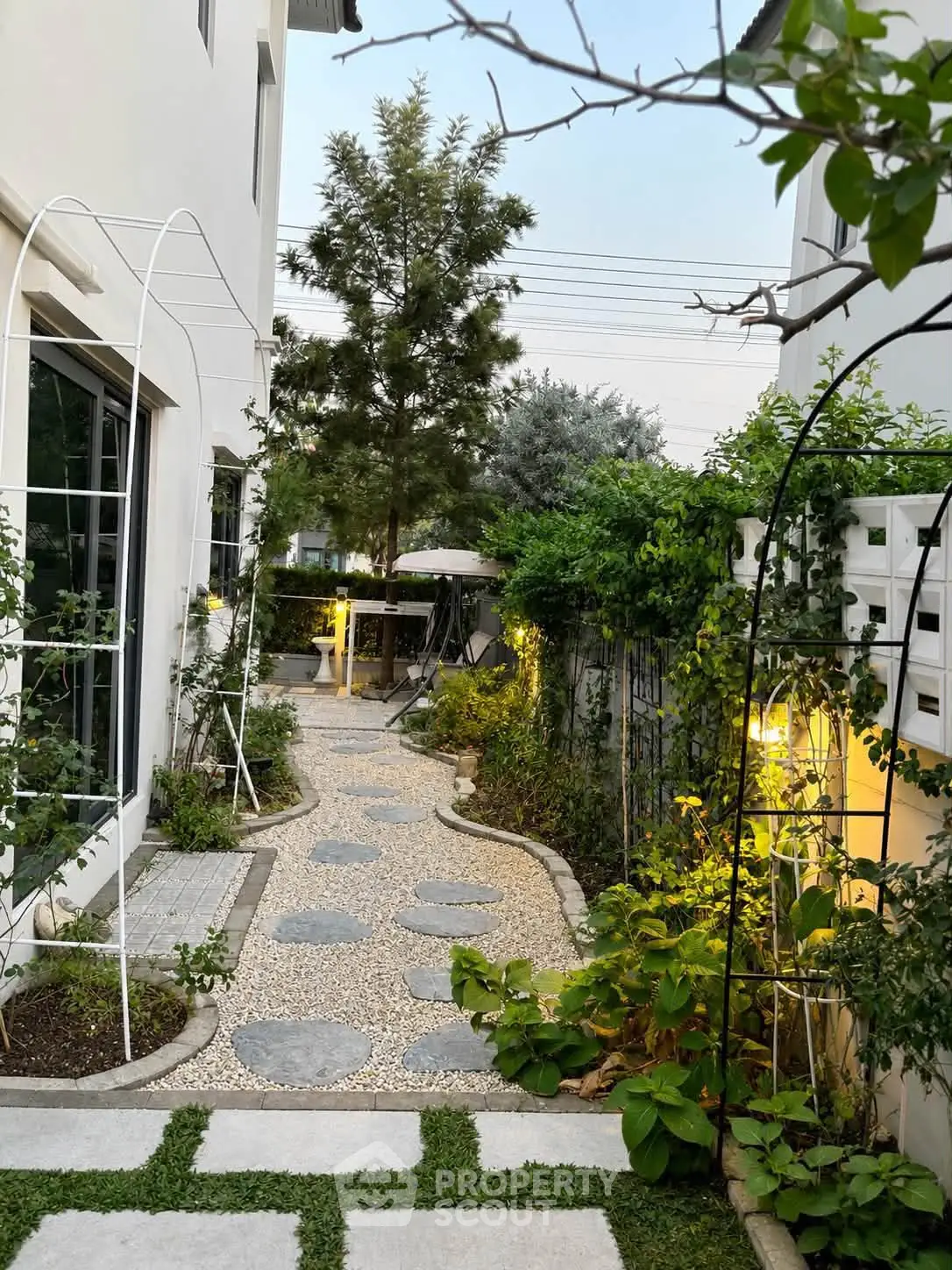 Charming garden pathway with lush greenery and ambient lighting in a modern residential setting.