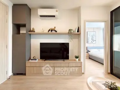 Modern living room with sleek TV unit and view into cozy bedroom