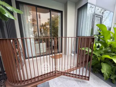 Charming balcony with lush greenery and modern sliding doors leading to a cozy interior.