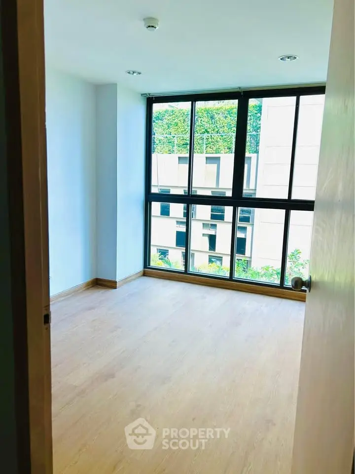 Bright empty room with large windows and wooden flooring, ideal for customization.