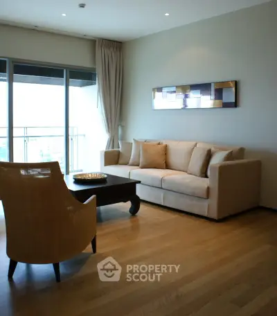Spacious living room with modern decor and large windows leading to a balcony.