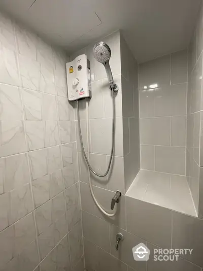 Modern bathroom shower area with sleek tiles and water heater