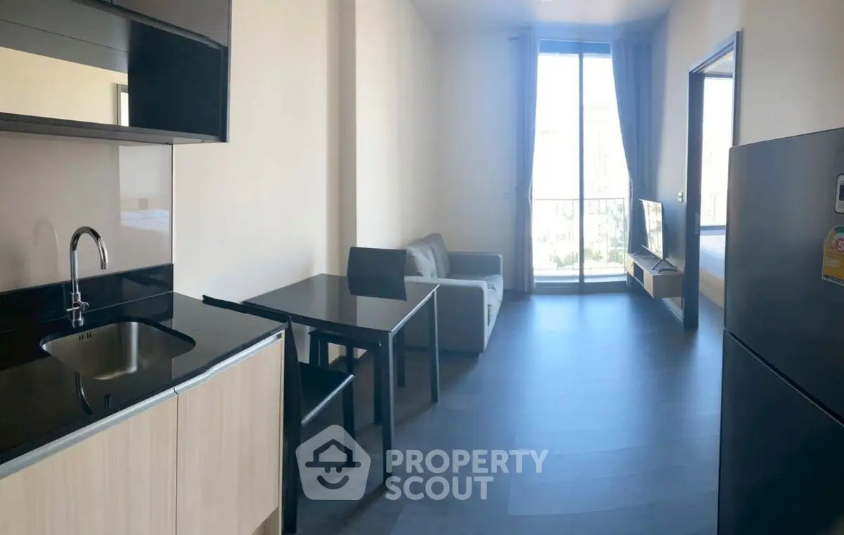 Modern studio apartment with sleek kitchen and cozy living area, featuring large windows and natural light.