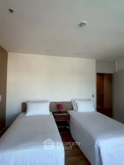 Cozy bedroom with twin beds and modern decor, perfect for relaxation.