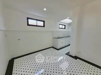 Spacious kitchen with modern black and white tiled flooring and ample natural light.