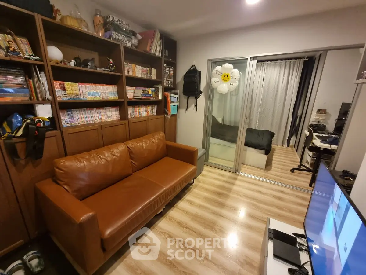 Cozy living room with brown leather sofa and sliding glass doors leading to a bedroom.