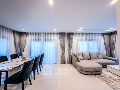 Luxurious living room with elegant dining area and plush seating, featuring floor-to-ceiling windows and modern decor.
