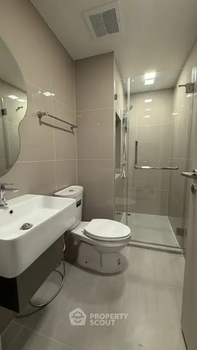 Modern bathroom with sleek design, featuring a glass shower enclosure and contemporary fixtures.